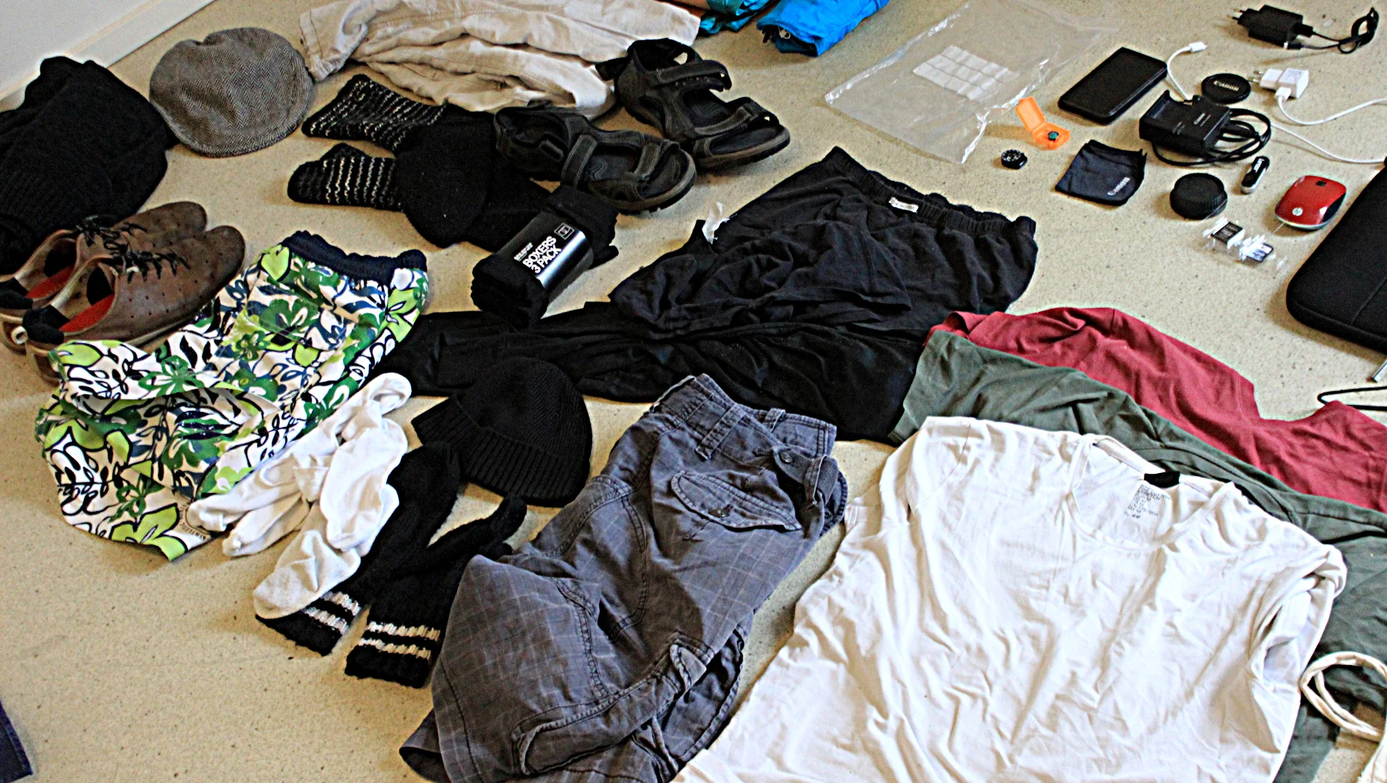 Round the world packing list. Clothes for a trip around the world spread on the floor.