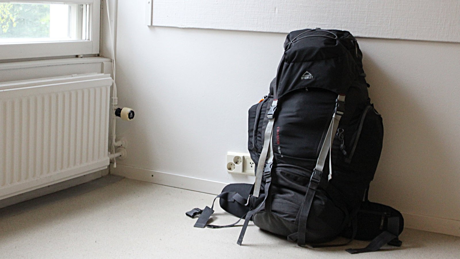 How to go on a trip around the world? Step one is packing. Pictured is a packed black McKinley backpack in an empty apartment.