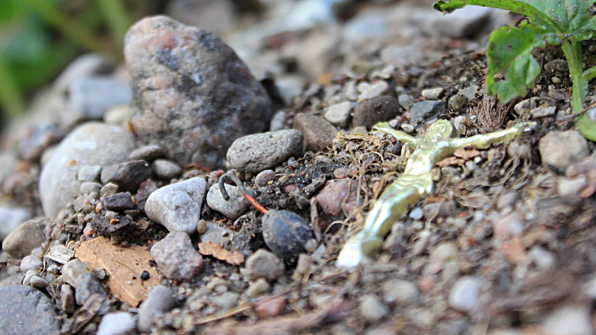 A miniature statue of Jesus lying on the ground beside small rocks.
