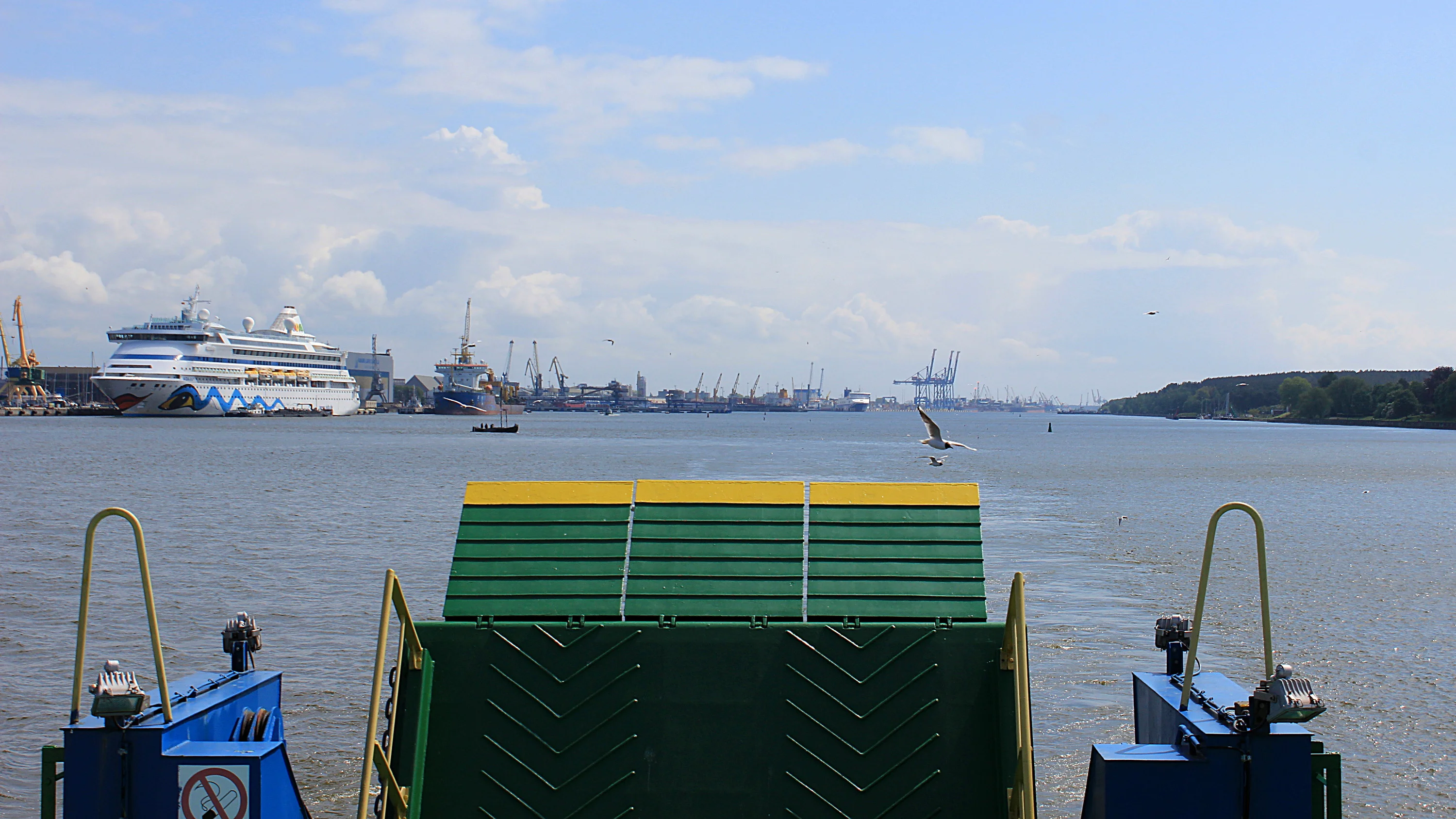 The back of the ferry to Curonian Spit with a green car ramp and a cruise ship in the background.
