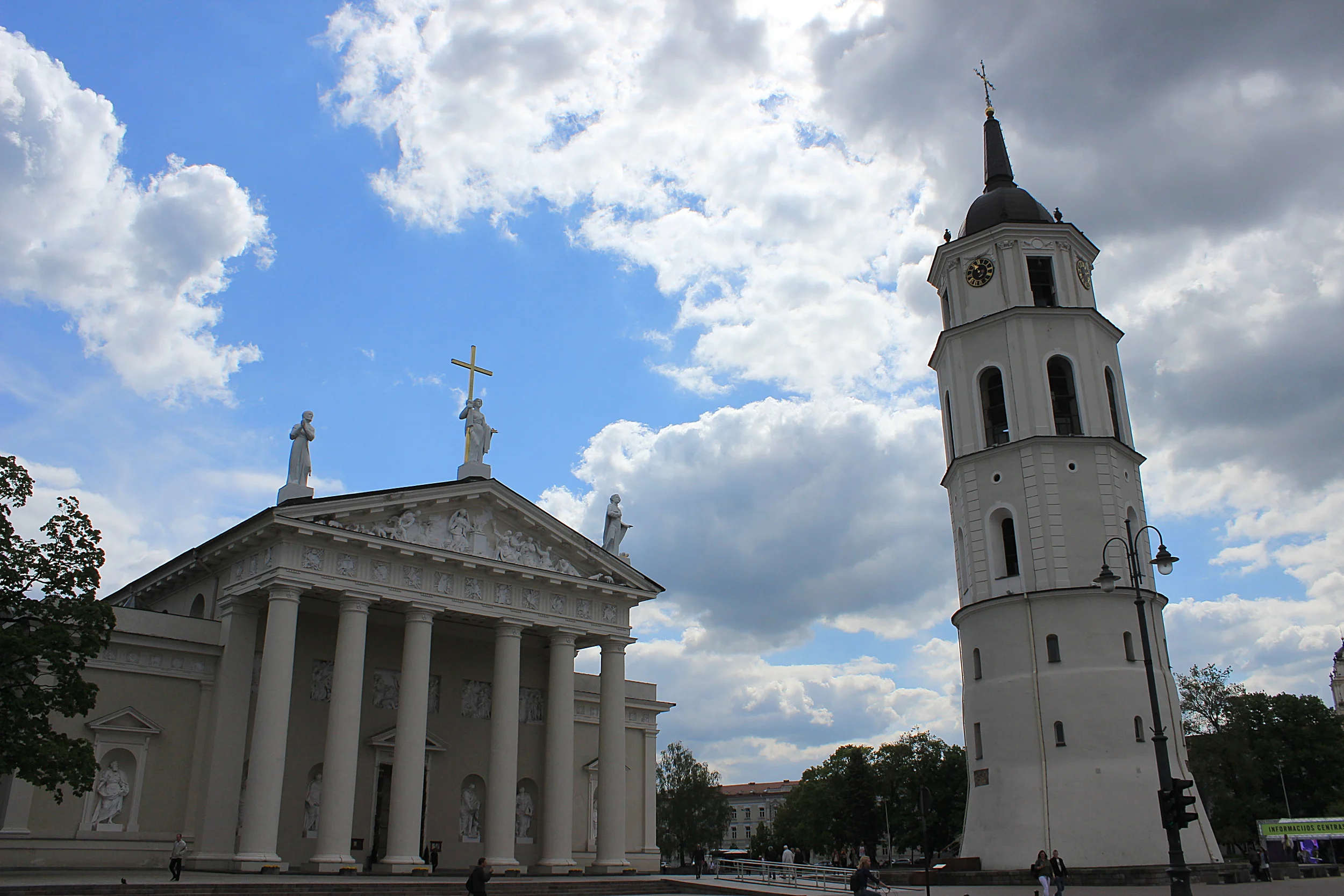 The Cathedral of Vilnius with white pillars, a tower in front and dramatic clouds in the background.