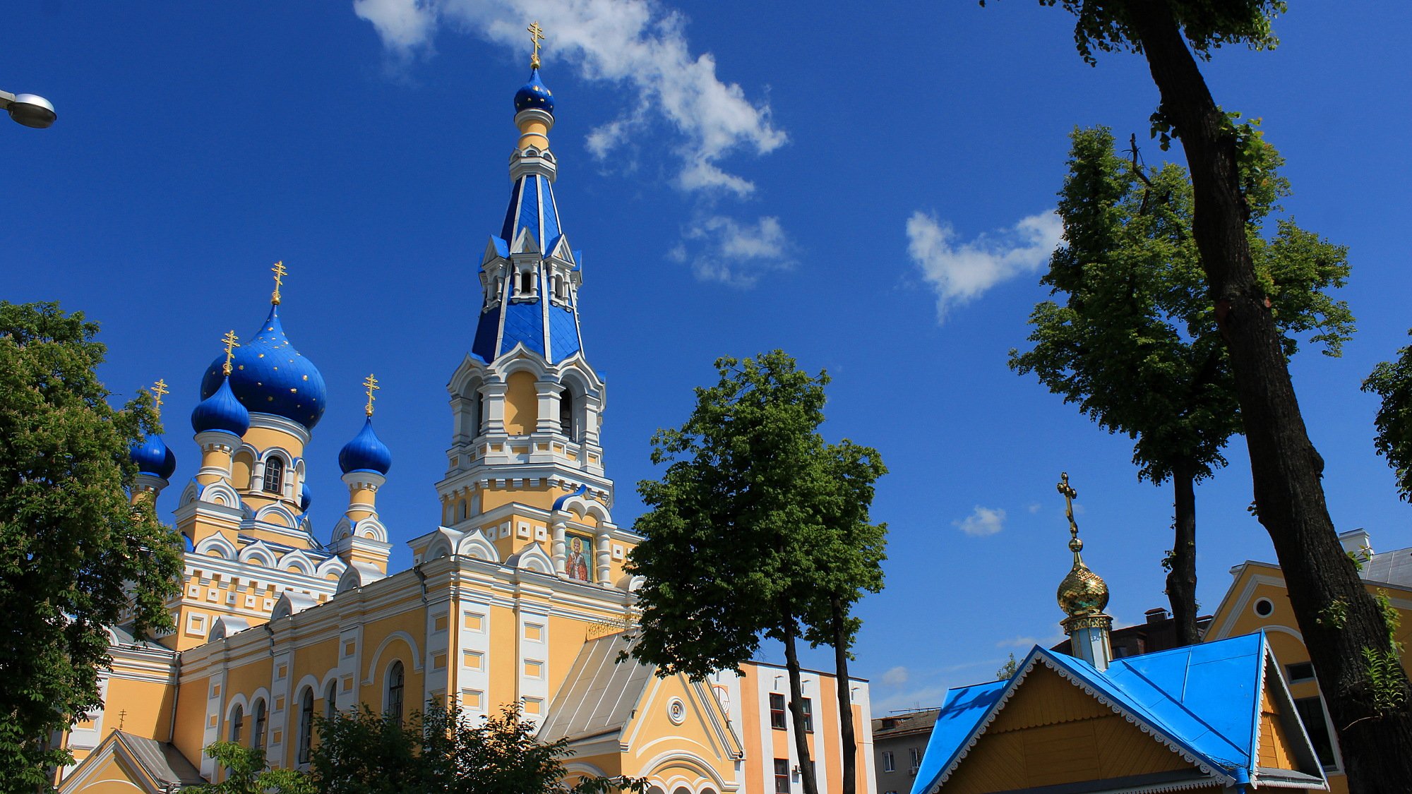 A colorful Orthodox church with yellow walls and blue domes in Brest, Belarus.