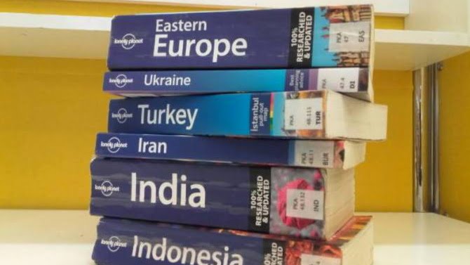 A pile of Lonely Planet guidebooks for Europe and Asia. How to prepare your mind for a trip around the world?