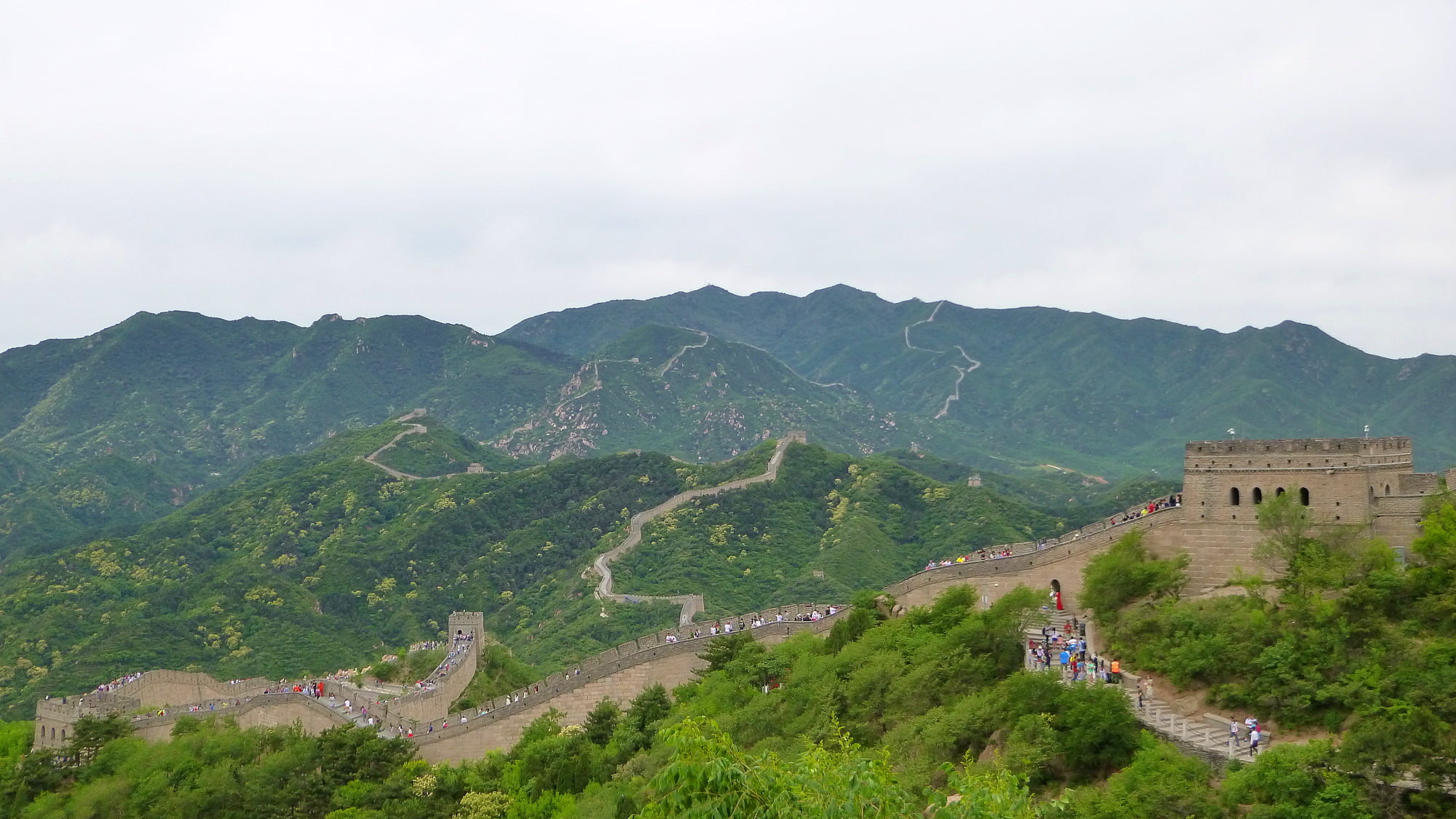 The Great Wall of China in Badaling with mountains and cloudy sky in the background.