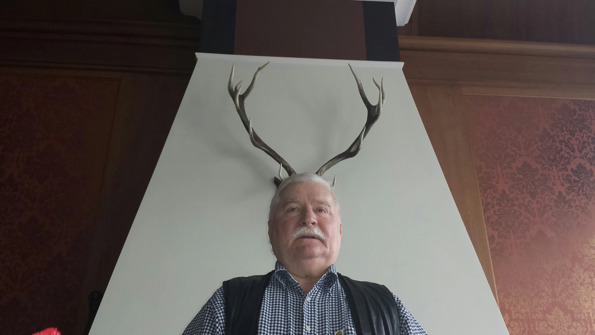 President Lech Wałęsa posing with deer or moose horns behind his head.