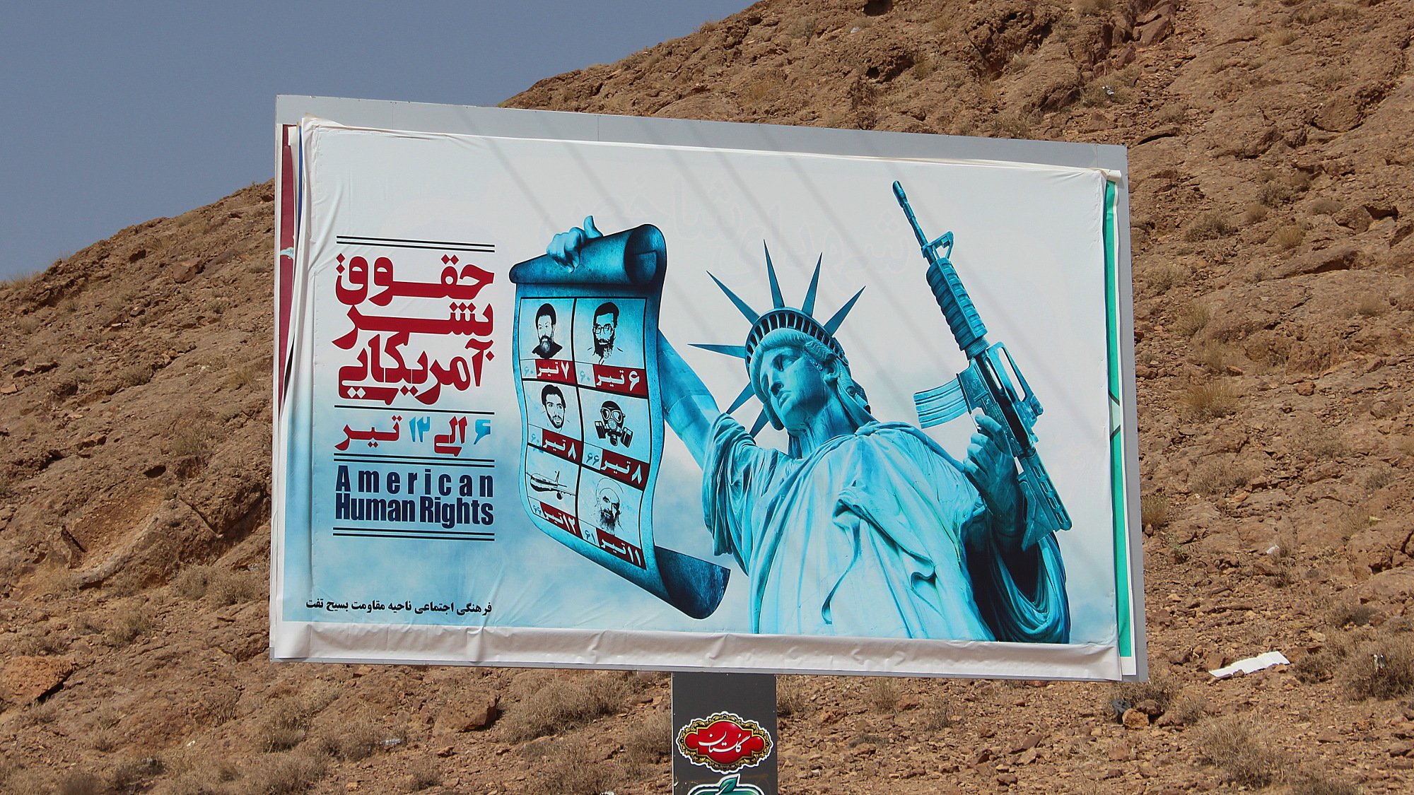 American Human Rights, an Iranian propaganda billboard on the side of the road. The Statue of Liberty holds a gun in one hand and pictures of the "nuclear martyrs" of Iran in other.