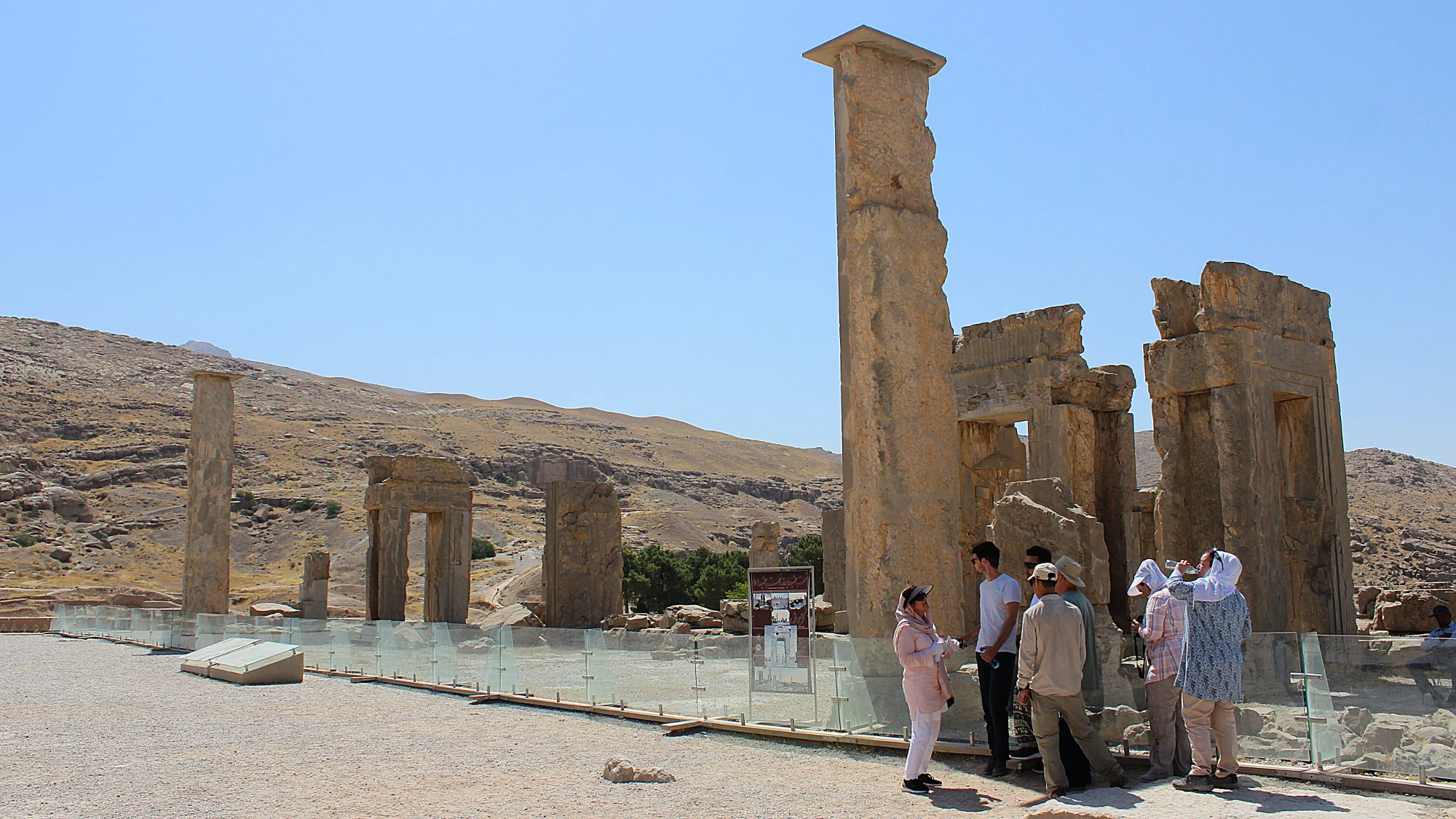 Tourist group taking shade behind a pillar at the ruins of Persepolis.