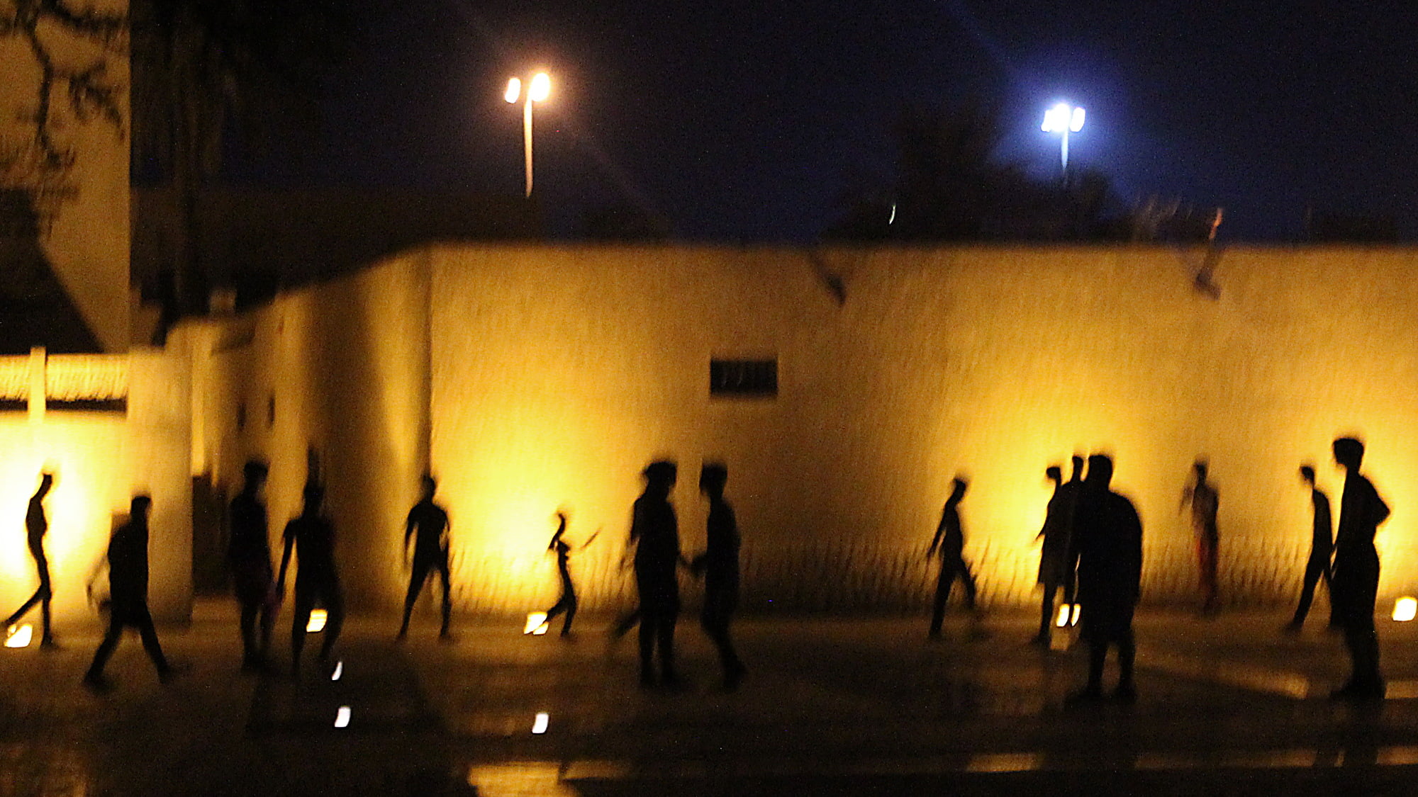 Silhouettes of children playing football at night.