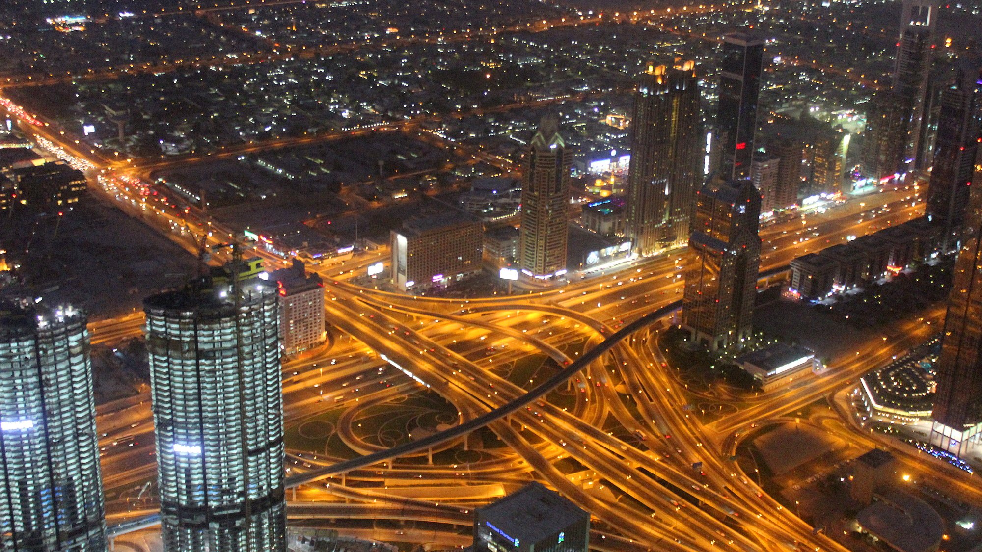 A view of Dubai from Burj Khalifa observation deck at night with lighted highways.