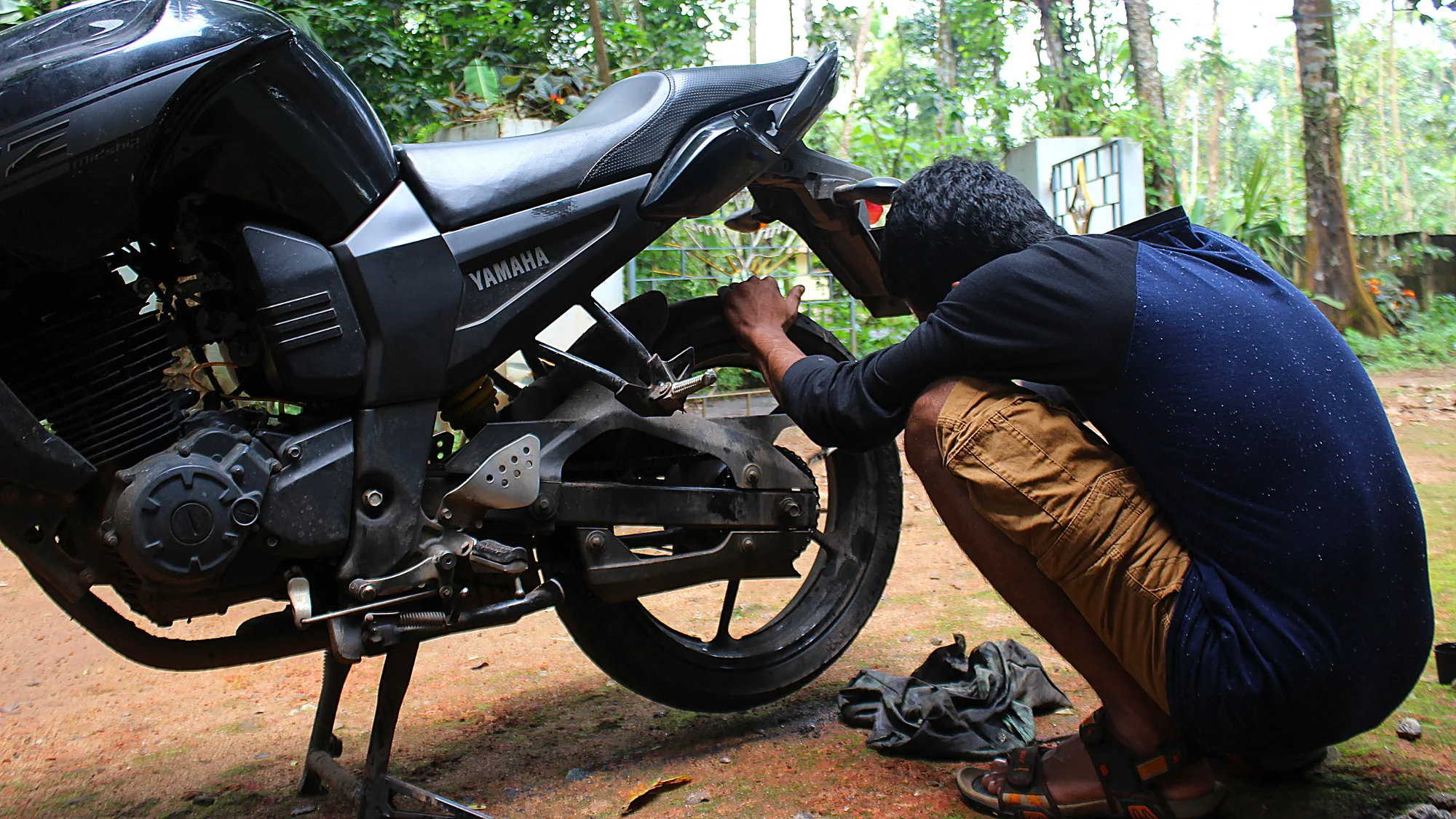 Indian man from Kerala maintaining a Yamaha motorcycle.