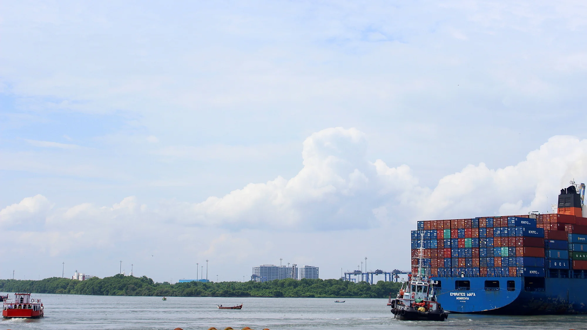 A massive cargo ship disappearing from the frame at the sea in front of Fort Kochi.
