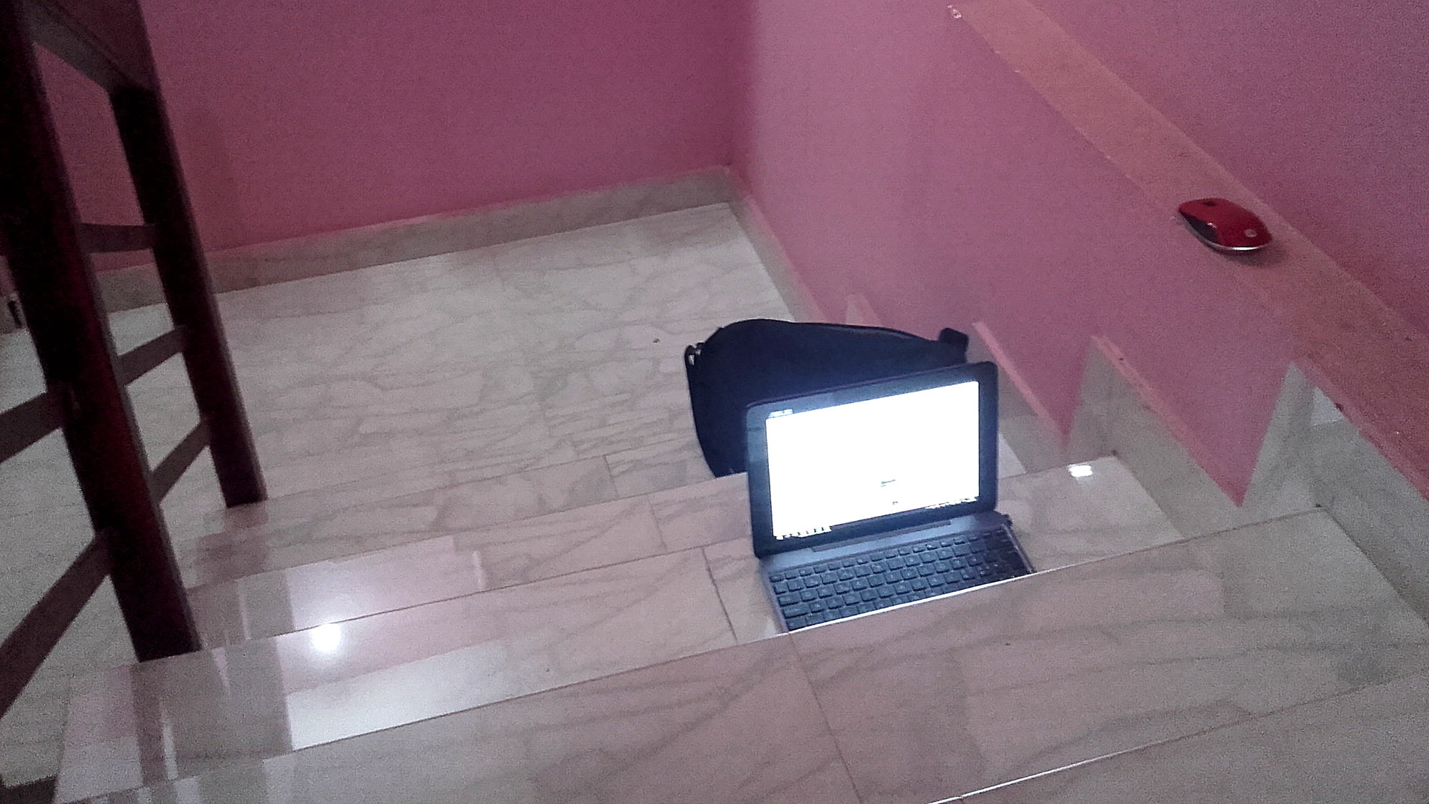 A laptop on a dark hotel stairway.
