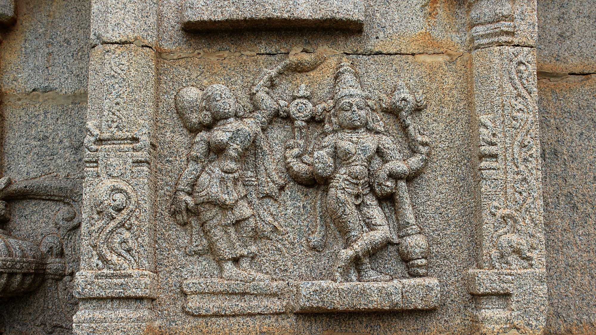 Small carvings of gods and goddessees on the stone wall of a temple in Hampi.