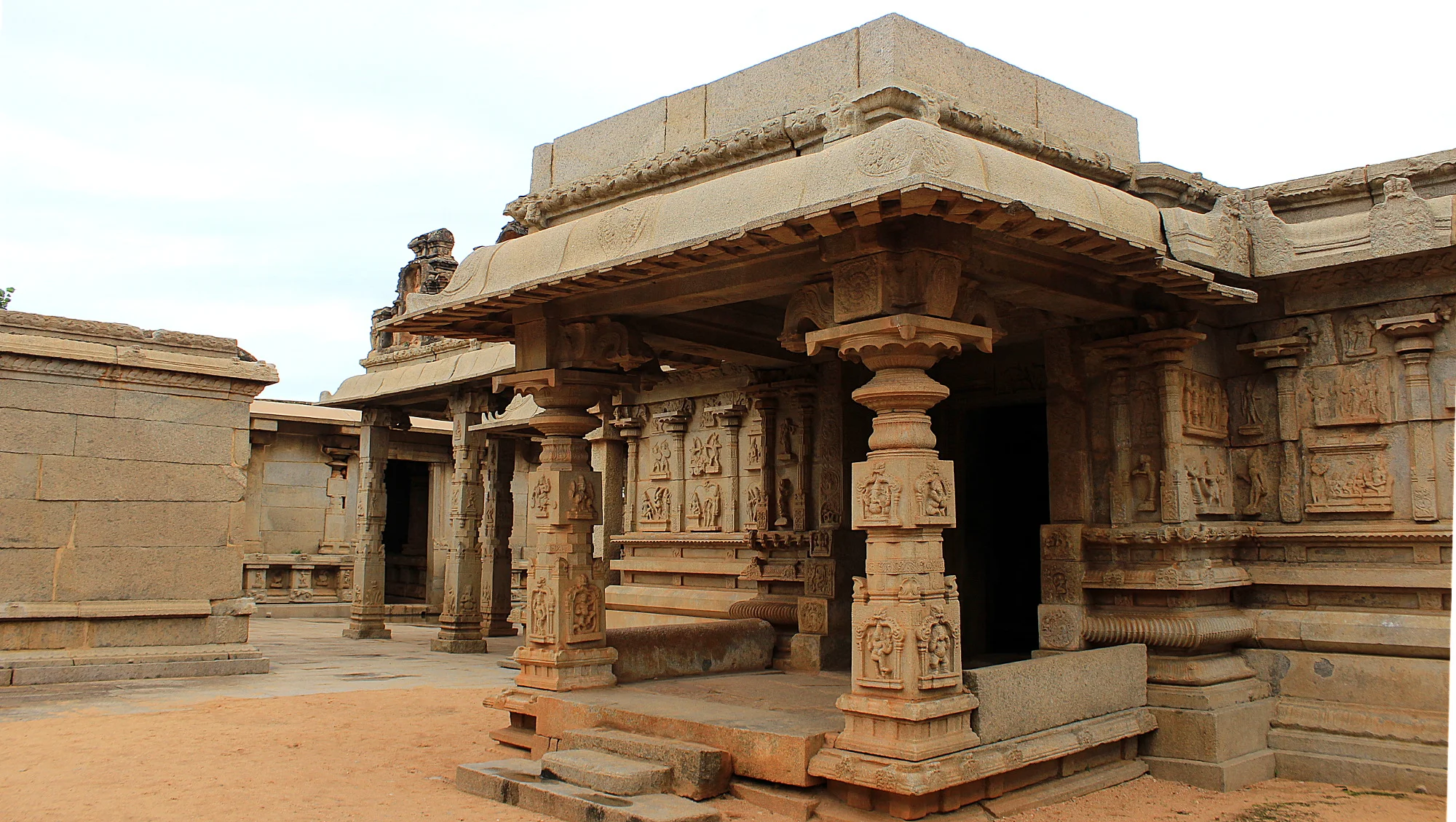 The ruins of Hampi. Light brown exterior of the Hazarama Temple with carved pillars.
