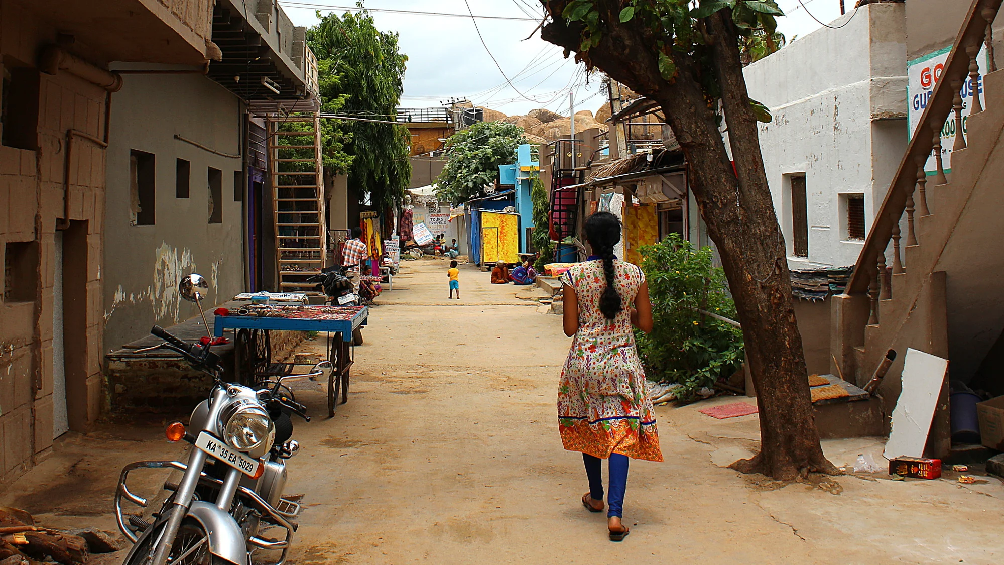 A quet street in Hampi Bazaar with a local woman walking away from the camera.