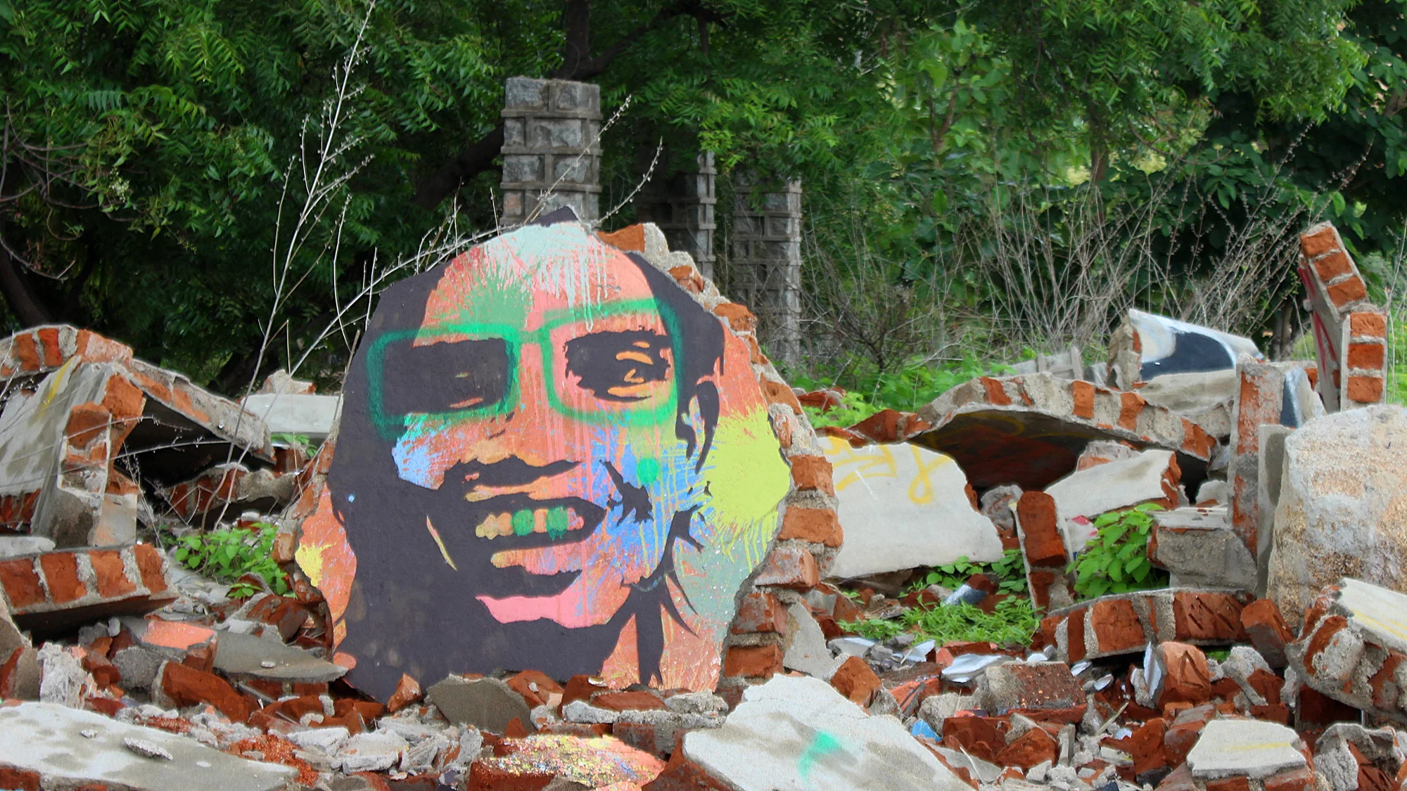 A colorful graffiti of a smiling man on a piece of concrete in Virupapur Gaddi.