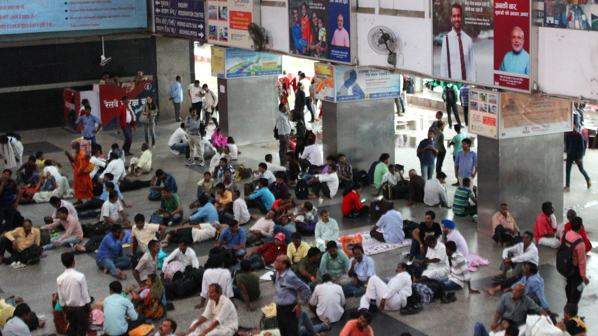 Indian people sleeping and waiting on the floor of the New Delhi railway station lobby.