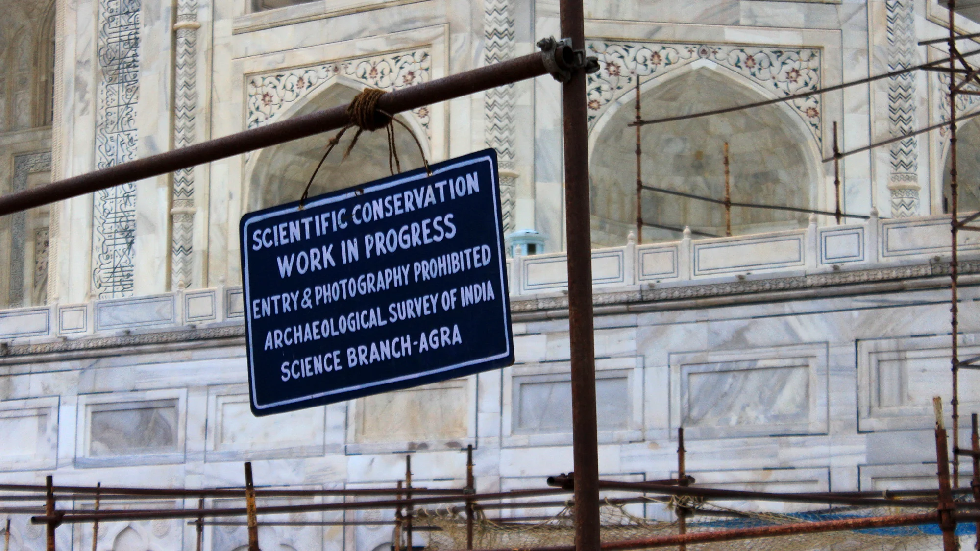 A sign that says "Scientific conservation work in progres - entry & photography prohibited. Archeological Survey of India, Science Branch-Agra" at Taj Mahal under renovation.