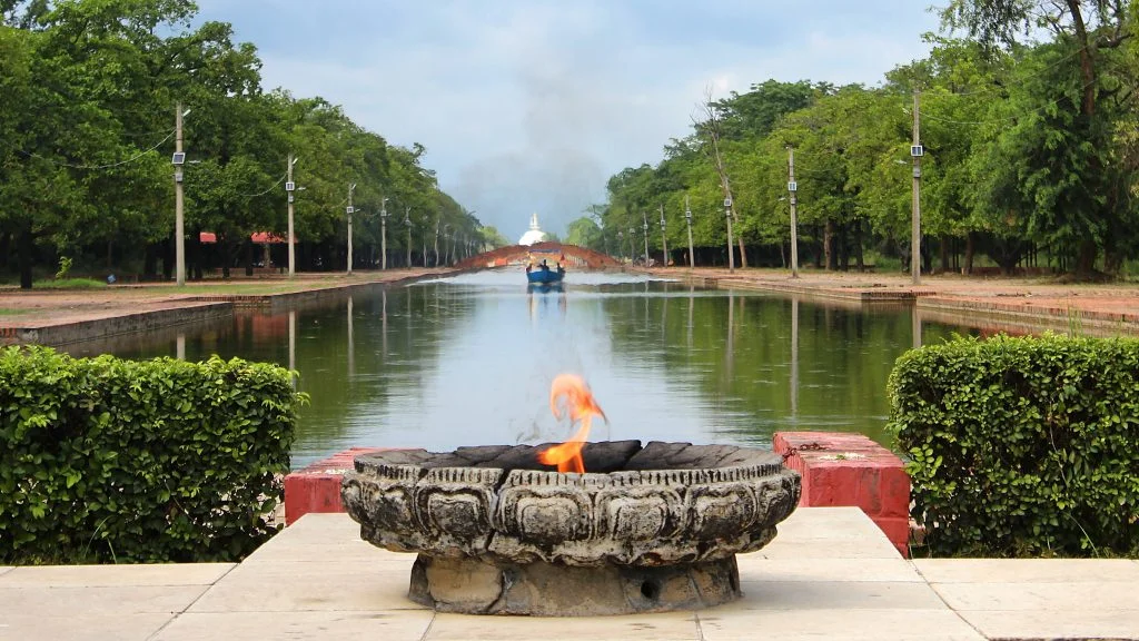 An eternal flame in Lumbini Development Zone with a body of water in the background.