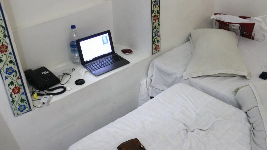 A laptop set on an inset on the wall with bed workings as a chair.