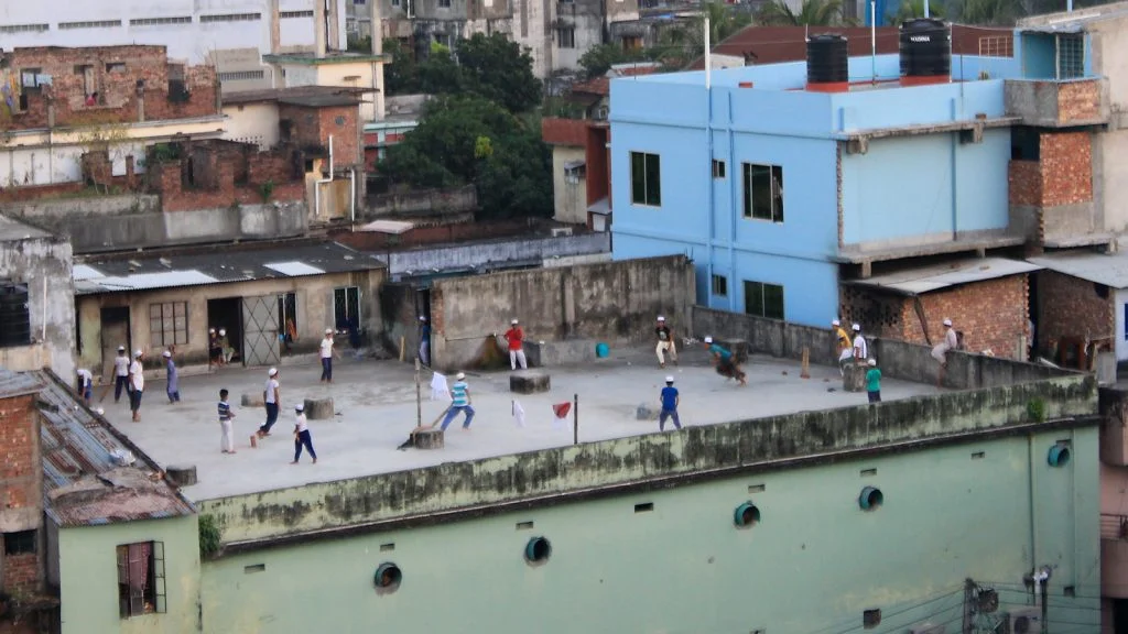 Young men playing cricket at a concrete rooftop in Khulna.