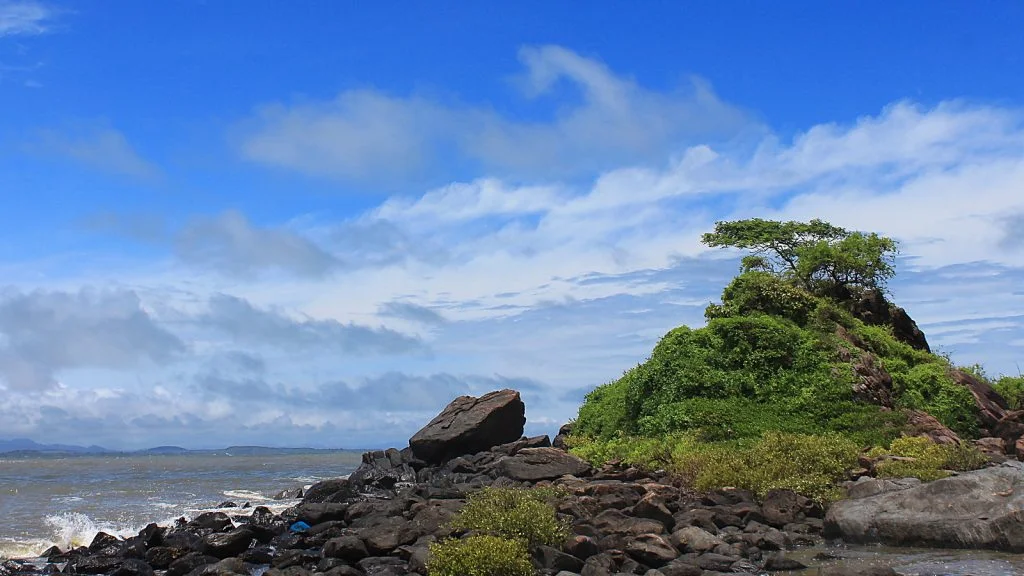 A cliff rising on the beach with waves hitting the rocks in Om Beach, Gokarna.