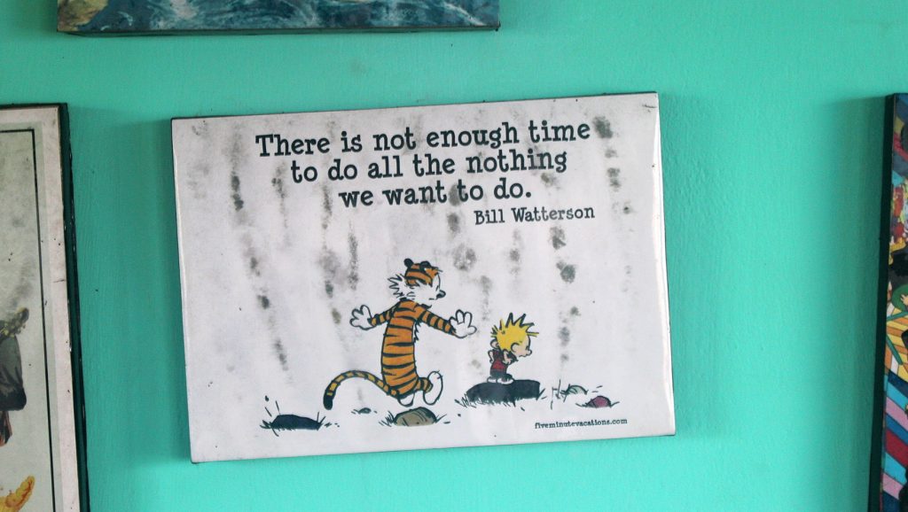 A Calvin and Hobbes quote print saying "There is not enough time to do all the nothing we want to do" hanging on the wall of Zostel Gokarna, India.
