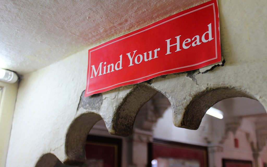 The psychology of travel. A red sign saying "mind your head" inside city palace, Udaipur.