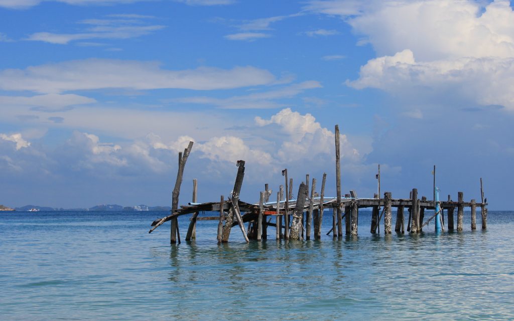 An old wooden dock out in the ocean with no connection to the coast in the island of Koh Samet, Thailand.