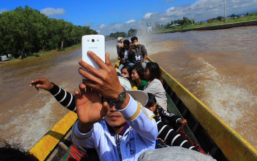 A guy from Myanmar taking selfie on a long boat in Inle Lake.