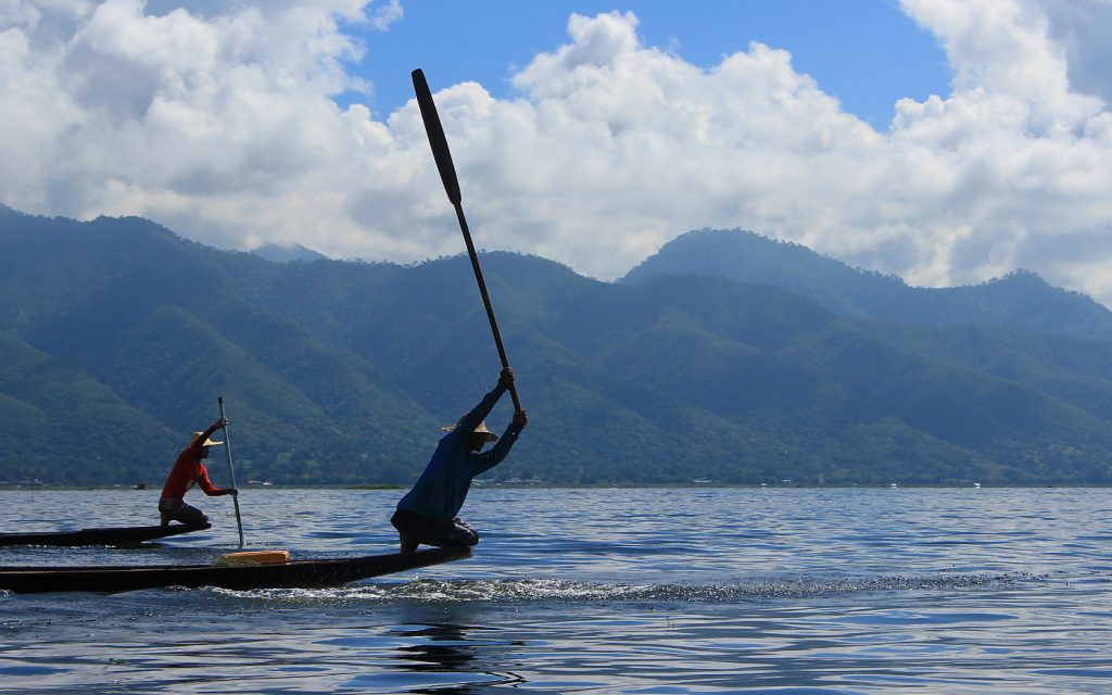 A local fisherman hitting water surface with a paddle in Inle Lake.