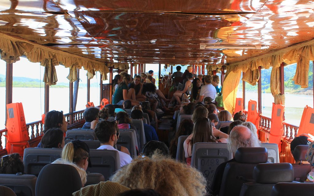 Inside the slow boat from Luang Prabang to Huay Xai, with passengers sitting on their chairs.