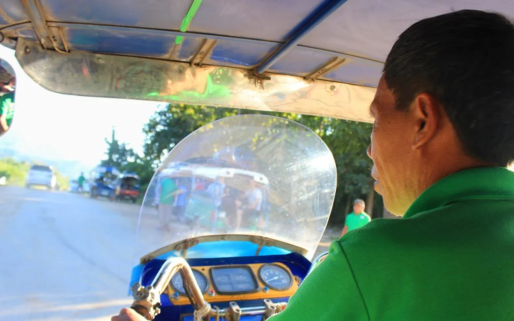 A tuk tuk rider in a green shirt driving to Luang Prabang in Laos.