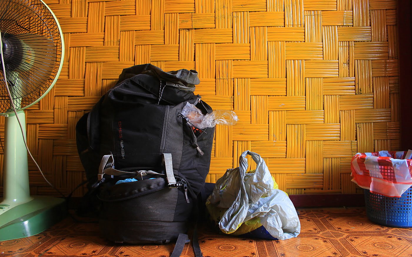 Most useful things to pack for a trip around the world. A black McKinley 65+10 liter backpack in a hostel room.