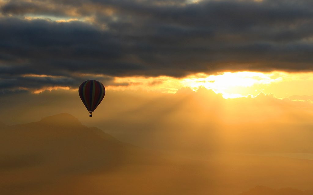 Hot air ballooning in Vang Vien, Laos. A hot air balloon flying against the sunrise in the background.
