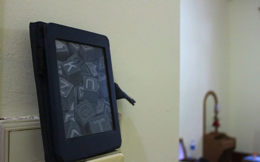 A 2nd generation Amazon Kindle Paperwhite model with the idle screensaver image.