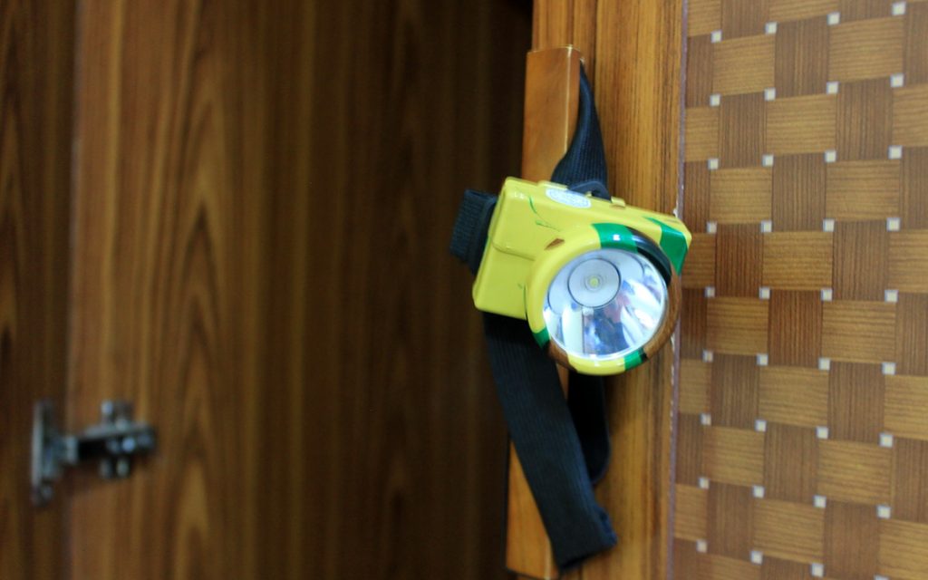A headlamp from Laos hanging on the door of a hotel room drawer.