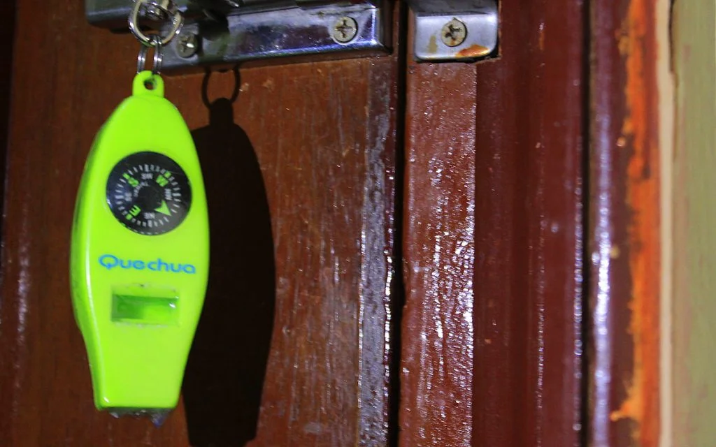 A green Quechua compass with a whistle and a thermometer.