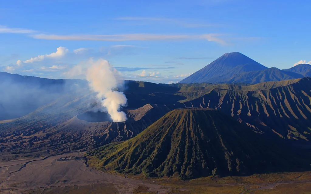 Mount Bromo (2392m) is the smoking crater on the left. The mountain in the front is Batok (2440m), while Java's highest mountain Mount Semeru (3676m) looms in the background.