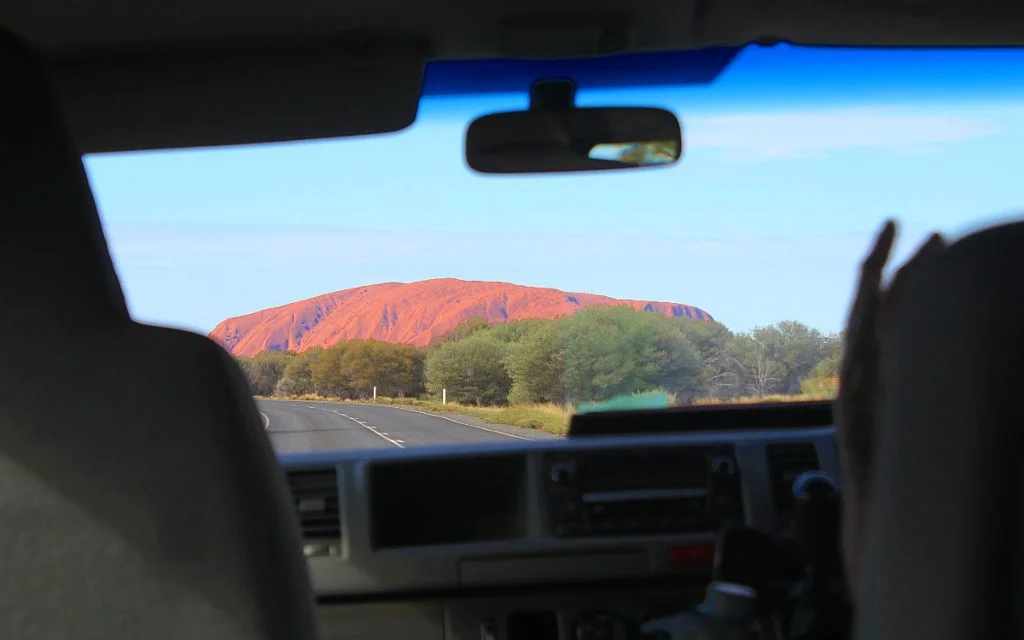 Uluru from far away inside a car.
