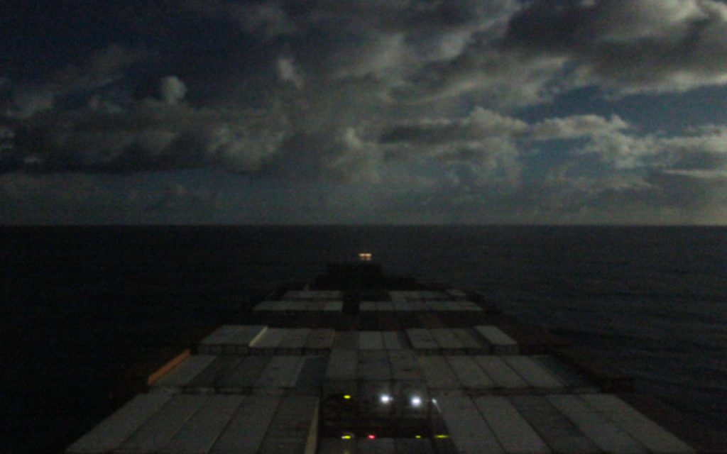 Traveling on a cargo ship across the Pacific Ocean during the night.