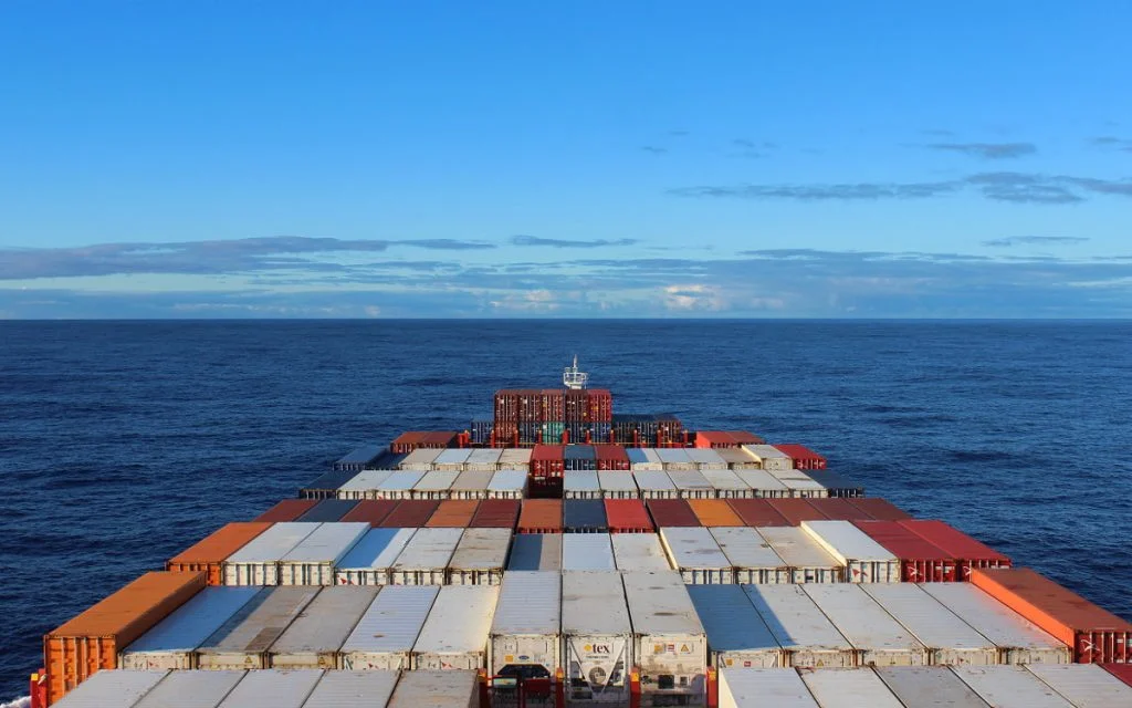 A cargo ship crossing the Pacific with clouds in the background.