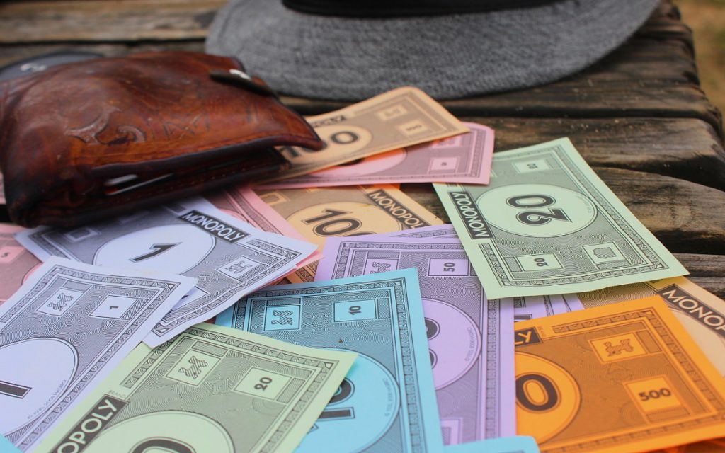 Monopoly money, a wallet and a hat on a dock in Fiji. Best long-term travel tips.
